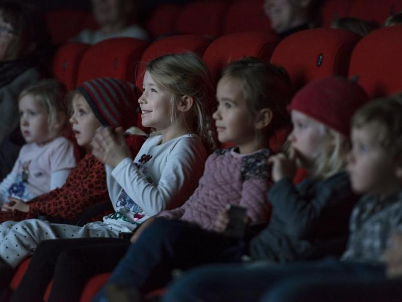 Glad børn sidder i biografmørket